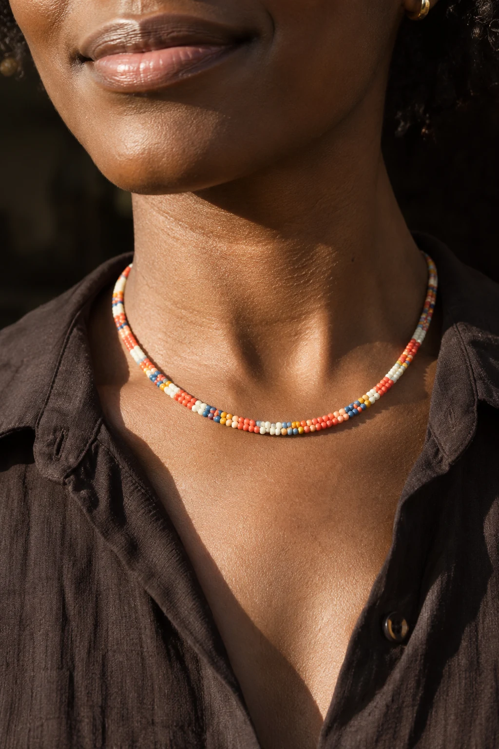 Una persona lleva un collar de pequeñas mostacillas de colores sobre el pecho.